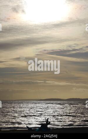 Exmouth kitesurf, Kitesurfer stagliano contro il Mare d'argento su un giorno di inverni al di sotto di un drammatico cielo nuvoloso. Devon, Regno Unito Foto Stock