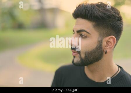 Vicino la vista di profilo del giovane bello uomo indiano pensando al parco Foto Stock