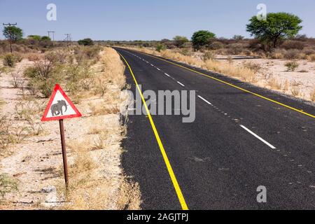 Lunga strada di catrame con segno animale, nel deserto di Kalahari vicino a Rakops, Distretto Centrale, Botswana, Africa Meridionale, Africa Foto Stock