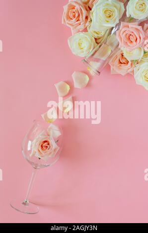 Rosa rosa in vetro del vino con i petali dalla bottiglia messo su sfondo rosa per il giorno di San Valentino. Flat Top laici visualizza il concetto di sfondo. Foto Stock
