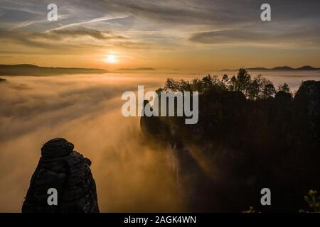 Colorato tramonto sull'rocky Neurathen Castello nel Parco nazionale di Svizzera Sassone, una fitta nebbia che copre la valle del fiume Elba Foto Stock