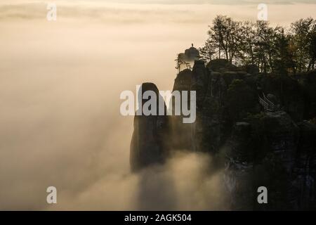 Sunrise over the rocky Neurathen Castello nel Parco nazionale di Svizzera Sassone, una fitta nebbia che copre la valle del fiume Elba Foto Stock