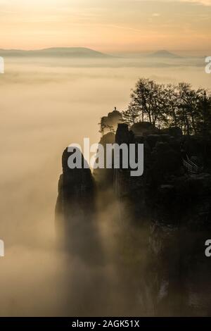 Sunrise over the rocky Neurathen Castello nel Parco nazionale di Svizzera Sassone, una fitta nebbia che copre la valle del fiume Elba Foto Stock