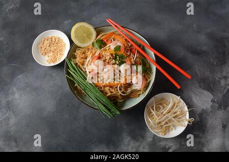 Pad Thai - piatto tradizionale tailandese con spaghetti di riso fritti, gamberi e verdure su sfondo scuro, spazio copia Foto Stock