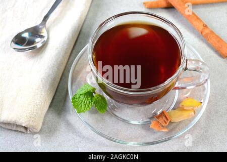 Tè alla menta alla cannella allo zenzero servito in una tazza da tè di vetro Foto Stock