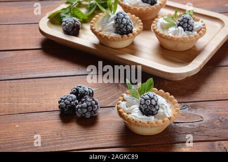Tartlet fatte in casa con mora, panna montata e menta. Gustoso dolce concetto Foto Stock