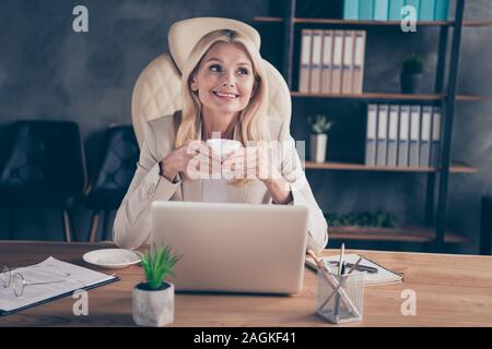 Foto di allegra ceo positivo tenendo tazza di tè con le mani seduti nella parte anteriore del computer avente rilassarsi con gli occhiali presi off Foto Stock