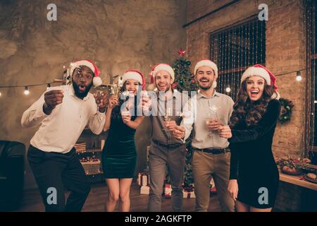 Ritratto di bella ragazzi ladies tenere il vetro di fuochi d'artificio godetevi il tempo di Natale celebrare X-mas mezzanotte indossando santa claus hat cap usura formale in casa Foto Stock