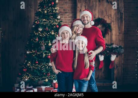 Buon Natale e felice newyear.Foto di papà, mamma sorella fratello avente migliori X-mas eve insieme vicino garland tree usura interni santa caps e rosso Foto Stock