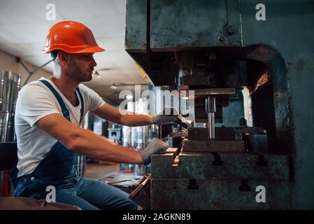 Mette una lastra di metallo in macchina. Uomo in uniforme lavora sulla produzione. Industriale la tecnologia moderna Foto Stock