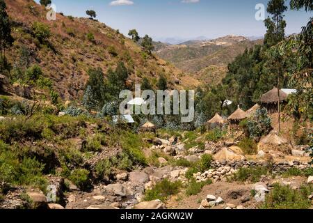 Etiopia, Amhara Region, Lalibela, Yemrehanna Kristos village, agricoltura, case di villaggio accanto a rocky river bed in stagione secca Foto Stock