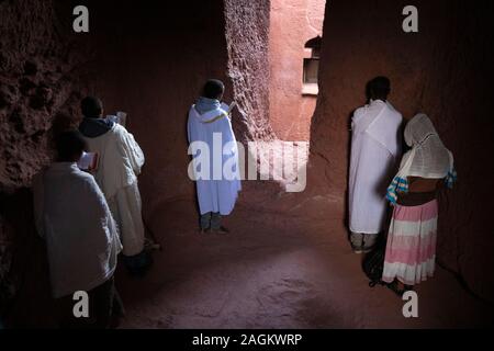 Etiopia, Amhara Region, Lalibela, Bet Gabriel Rafael, adoratori di pregare al di fuori della chiesa dalla finestra Foto Stock