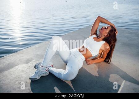 In posa per la fotocamera. Giovane donna fitness con corpo sottile tipo è all'aperto Foto Stock