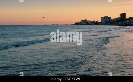 Piano di atterraggio in Larnaca. Bella serata il tramonto sul mare e dello skyline della citta'. Foto Stock