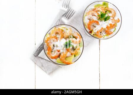 Pasta con insalata di gamberetti, avocado, Fresco cetriolo e peperone e pomodoro condito con salsa di yogurt in due bicchieri di vetro su un tovagliolo, pane e delle forcelle Foto Stock