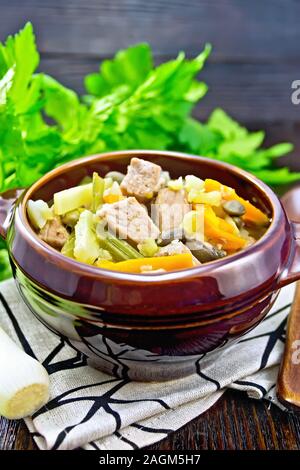 Eintopf zuppa di maiale, sedano, i fagioli, le carote e le patate con il porro in un vaso di argilla su legno scuro board Foto Stock