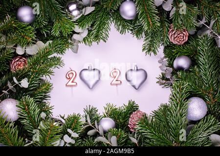 Numeri 2020 con rami di un albero di Natale su uno sfondo bianco con una decorazione a sfere e coni Foto Stock