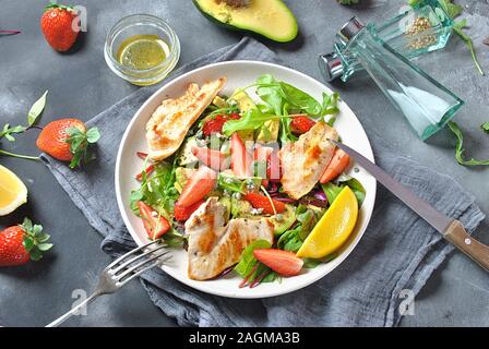 Insalata di pollo con avocado, fragole, formaggio blu, rucola, foglie di barbabietola. Pranzo sano avocado ciotola, piatto con pollo e fragole Foto Stock