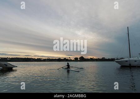 Femmina in canoa in acqua sotto a. cielo nuvoloso Foto Stock