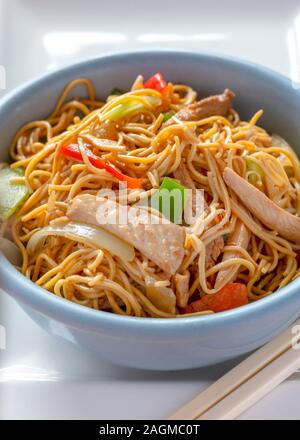 Verticale del delizioso piatto di pollo Chow Mein con verdure e i bastoncini , sfondo luminoso per spazio di copia Foto Stock