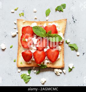 Toast con frutta fragola, menta e formaggio per colazione. Una sana prima colazione, Rubicondo pane tostato. Tradizionali americani e europei estivi bre Foto Stock