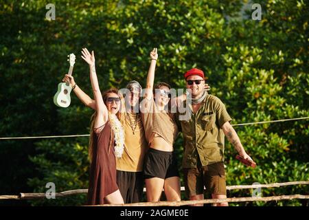 Gruppo di felice entusiasti amici in occhiali da sole alzando le mani e godendo le vacanze estive Foto Stock