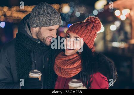 Foto di due persone divertenti coppia con bevanda calda nelle mani di spendere X-mas sera insieme avendo miglior tempo libero indossa cappotti caldo a maglia e tappi Foto Stock