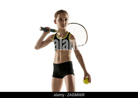 Piccola ragazza caucasica giocando a tennis su bianco di sfondo per studio. Modello di cute che pongono fiducia e calma in motion, azione. La gioventù, flessibilità e potenza ed energia. Annuncio, sport, stile di vita sano concetto. Foto Stock