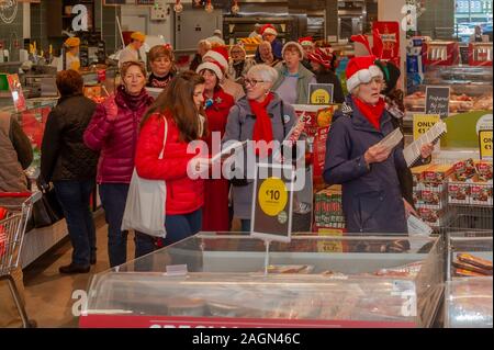 Bantry, West Cork, Irlanda. Xx Dec, 2019. Bantry Coro della Comunità terrà una improvvisata performance in un supermercato a Bantry oggi. Hanno speso tempo a piedi il giro del negozio divertente gli acquirenti da canti natalizi. Credito: Andy Gibson/Alamy Live News. Foto Stock