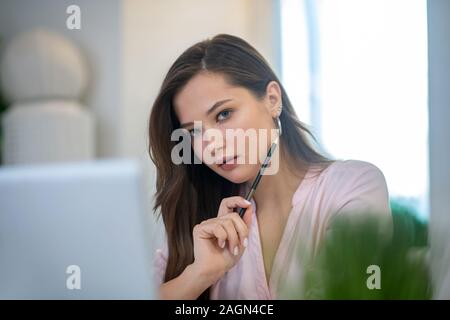 Bella giovane donna tenendo la sua matita Foto Stock