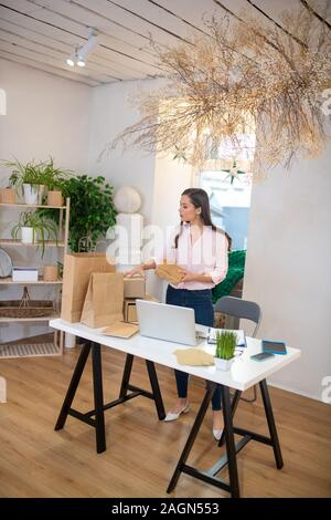 Bella giovane donna preparare regali per i suoi amici Foto Stock