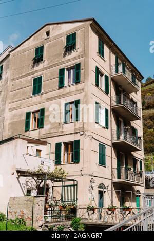 Aprire i balconi e persiane in legno. Residenziale casa vecchia in Italia con balconi. Di grandi dimensioni a più piani casa grigio Foto Stock