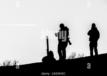 Una immagine in bianco e nero di un fotografo stagliano su una collina. Foto Stock