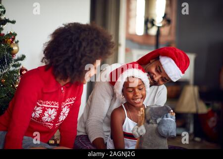 Famiglia allegra decora un Natale insieme e giocare con la ragazza carina Foto Stock