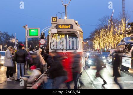 Tram di Vienna; la gente che attraversa la circonvallazione Universitatsring davanti a un tram ferma a una fermata di tram di notte, nel centro di Vienna, Vienna Austria Europe Foto Stock