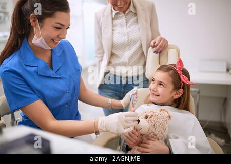 Dentista dando lollipop al bambino dopo il controllo in alto Foto Stock