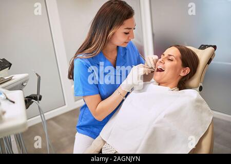 Dentista femmina trattare la donna in poltrona odontoiatrica Foto Stock