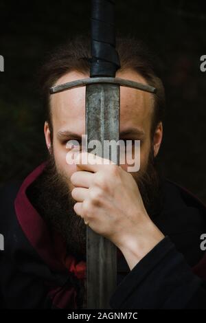 Ritratto di un cavaliere che tiene una spada in faccia. Foto Stock