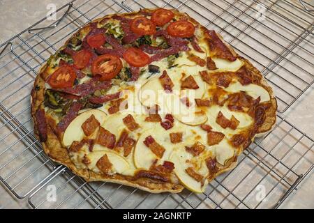 In casa apple la pancetta e il salame vegetale pizza raffreddamento su rack di asciugatura Foto Stock