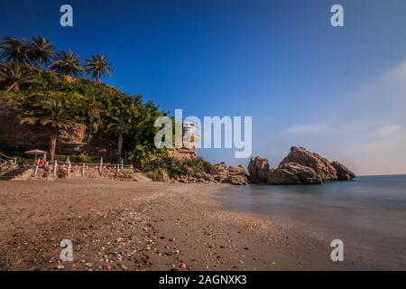 Piccola spiaggia di sabbia sulla costa spagnola di Costa del Sol. Balcon Europa a Nerja sulla giornata di sole come una vista sul Mediterraneo. Vista di rocce con palm Foto Stock