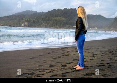 Luminose ritratto di un attraente donna bionda in piedi sull'oceano da qualche parte sulle rive del nord della California, Stati Uniti d'America Foto Stock