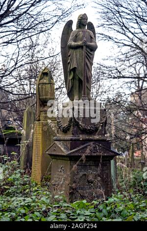 La figura di un angelo sorge su un monumento in un incolto e molto trascurato Dalry cimitero di Edimburgo, Scozia, Regno Unito. Foto Stock