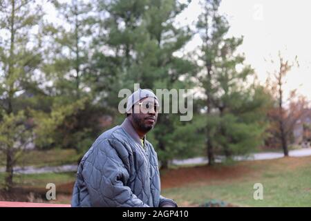 Un ritratto di un afro-americano di uomo in piedi fuori in grigio di una giacca invernale