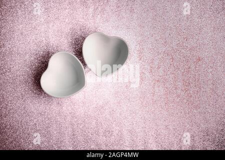 Due tazze di ceramica a forma di cuore su un dipinto di strutturato sfondo per una festosa design romantico per un matrimonio, il giorno di San Valentino, compleanno Foto Stock