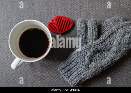 Cuori rossi, tazza di caffè e guanti invernali grigi Foto Stock
