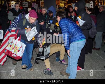 Chicago, Illinois, Stati Uniti d'America. 17 dicembre 2019. I dimostranti nel rally Federa Plaza, quindi marzo al Trump Tower esigente impeachment del Presidente Trump. Un membro del Partito Comunista è aiutato fino dopo essere stato spinto a terra da un altro manifestante in Federal Plaza. Foto Stock