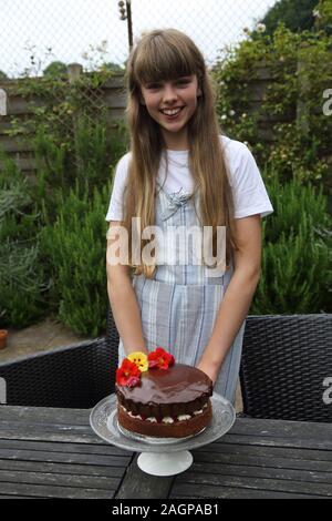 Tredici anni di ragazza con il suo cioccolato artigianale Pan di Spagna Birmingham Inghilterra Foto Stock