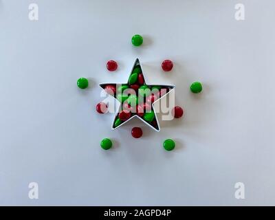 Orlando,FL/USA-12/20/19: Stella formina riempito con gustosi piatti di colore rosso e verde M&M tipo pulsante cioccolato candy tratta su una tavola di legno. Foto Stock