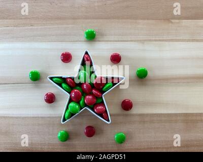 Orlando,FL/USA-12/20/19: Albero di Natale formina riempito con gustosi piatti di colore rosso e verde M&M tipo pulsante cioccolato candy tratta su una tavola di legno. Foto Stock