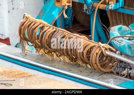 Anelli di acciaio sul lato di una piccola barca da pesca nel porto di Catania, in Sicilia, Italia. Foto Stock